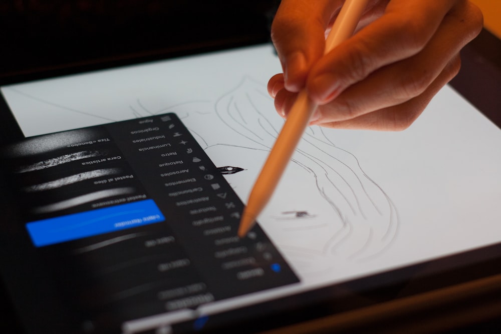 person holding stylus pointing on drawing pad