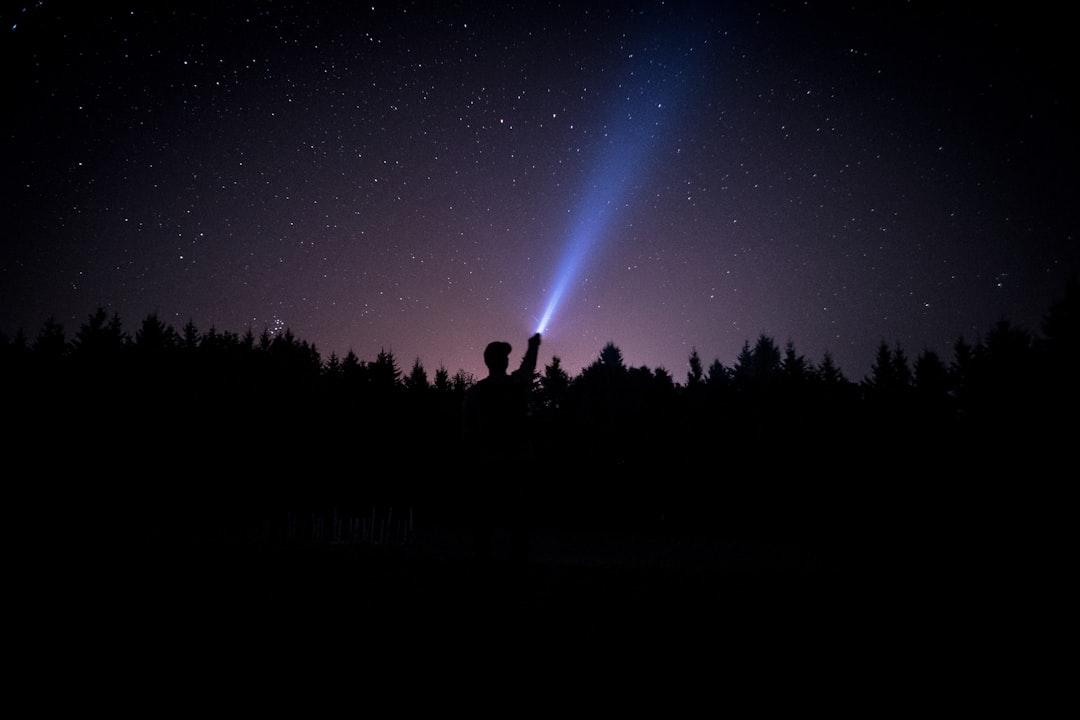 silhouette of person holding flashlight during nighttime