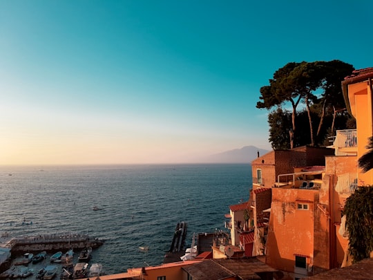 white concrete house near body of water under blue sky during daytime in Sorrento Italy