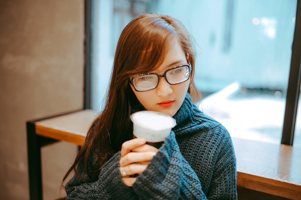woman in gray knit jacket holding cup