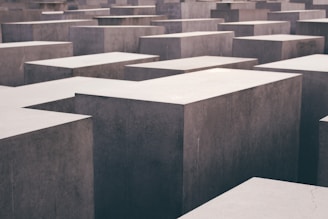 Numerous large, rectangular concrete slabs are arranged in a grid-like pattern, appearing at varying heights and creating an abstract geometric effect.