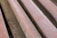 Several rusted metal beams or bars arranged in parallel, showing a reddish-brown coloration due to oxidation. The surface appears rough with visible textures and rust marks.