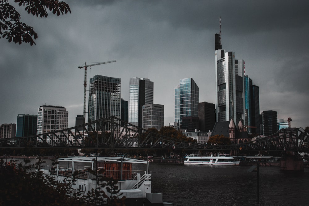 white boat near suspension bridge under nimbus clouds