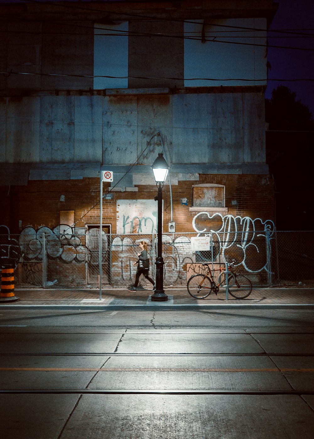 woman walking near black lamppost turned-on during nighttime