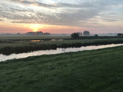 A serene landscape with a sunrise over a calm river.