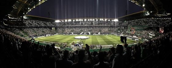 A lively stadium scene capturing fans passionately watching a Premier League match under floodlights.