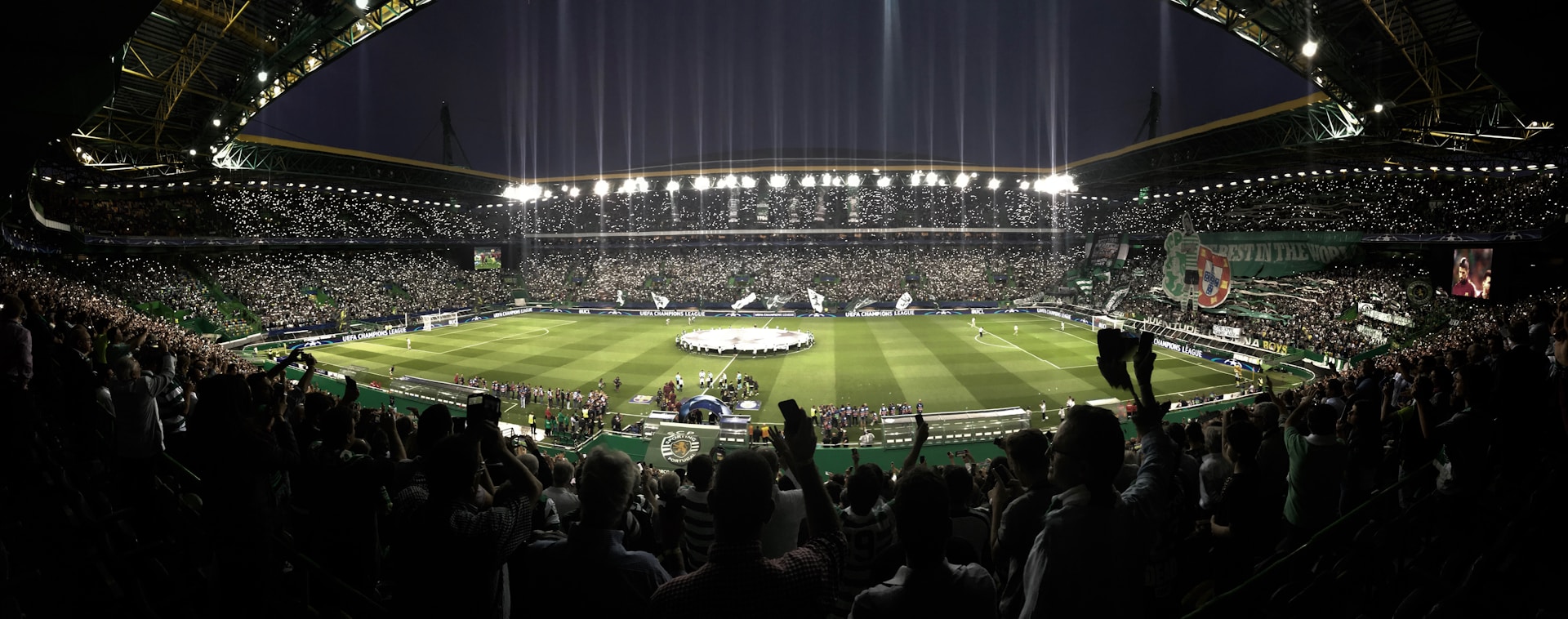 A panoramic shot capturing the sea of fans filling the stands under bright stadium lights, ready for the game to begin.