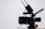 A professional video camera with a large lens and an attached external monitor. Two antennas are mounted on top, likely part of a wireless transmission system. The camera is on a tripod, set against a simple, light-colored background.