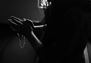 silhouette of woman holding rosary while praying