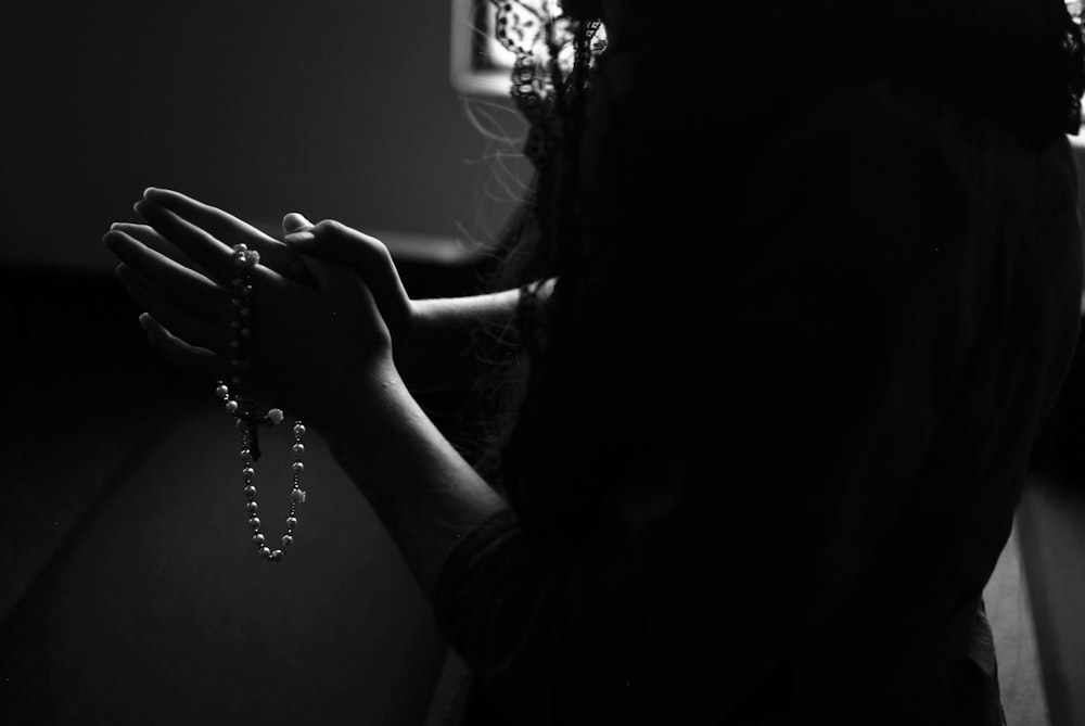 Silhouette einer Frau, die beim Beten einen Rosenkranz hält