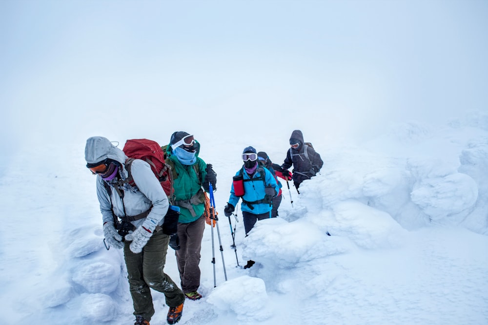 four people trekking on snow