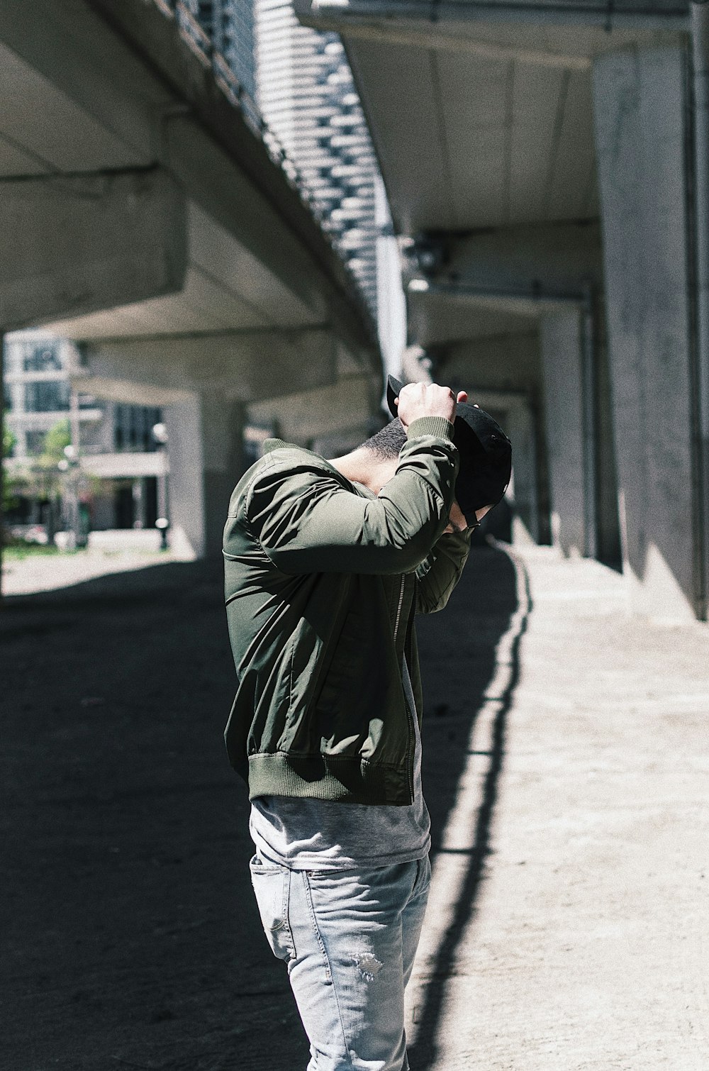 man in green jacket under overpass during daytime