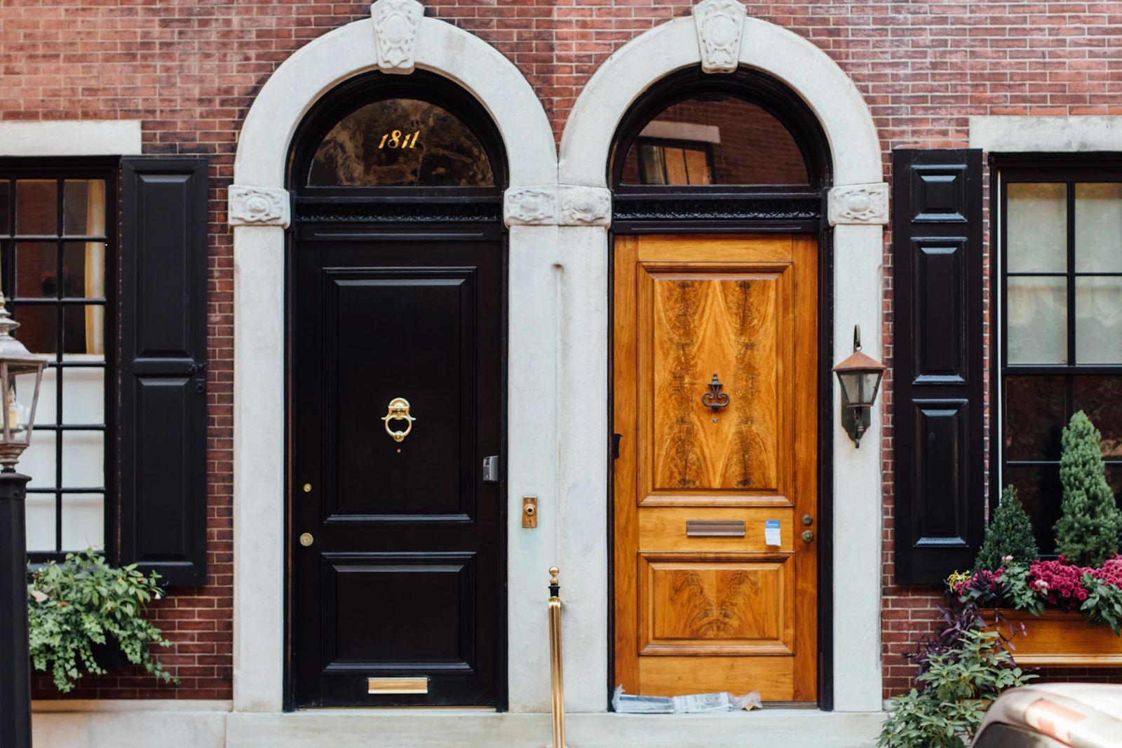 Two front doors side by side on the same building, one black and one wood
