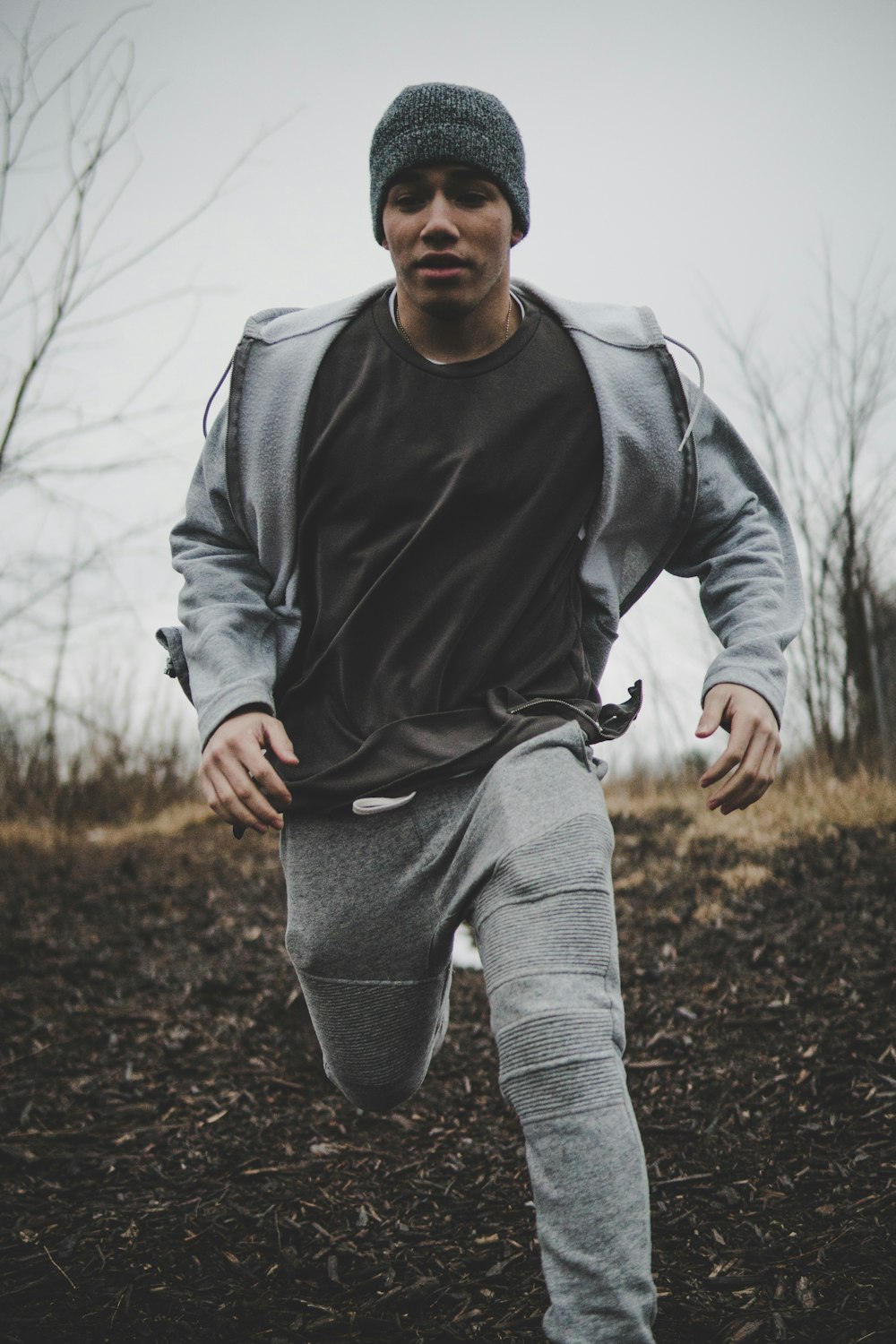 homme portant une chemise noire et une veste grise avec un pantalon tout en courant dans un champ uni