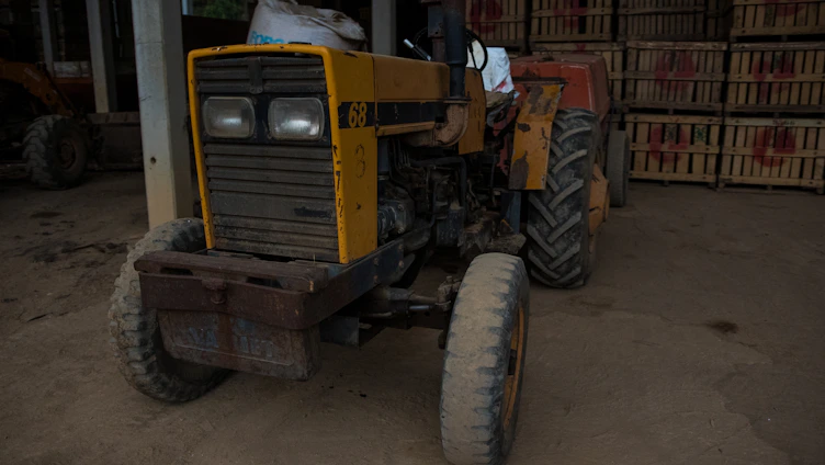 A tractor undergoing maintenance in a rural workshop surrounded by farming tools.