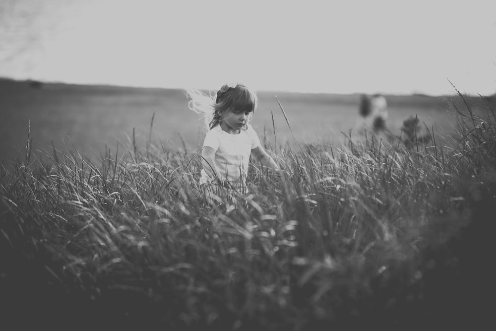 grayscale photography of girl standing on grass field