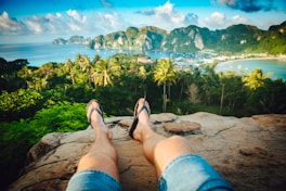 person wearing black flip-flops sitting on rock