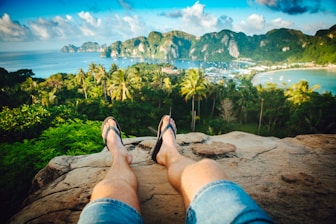 person wearing black flip-flops sitting on rock