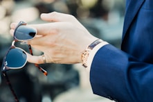 shallow focus photography of man holding sunglasses