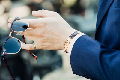 shallow focus photography of man holding sunglasses style teams background