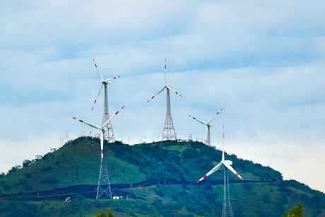 Engineers collaborating over renewable energy project plans with wind turbines in the background.