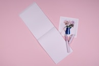 Close-up of a pastel pink notebook with handwritten product notes and a delicate pen.