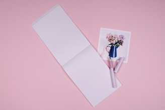 Close-up of a pastel pink notebook with handwritten product notes and a delicate pen.