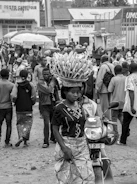 woman carrying bunch of banana on head walking near motorcycle