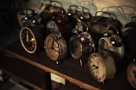 Antique pocket watches and old-fashioned clocks arranged on a rustic shelf.