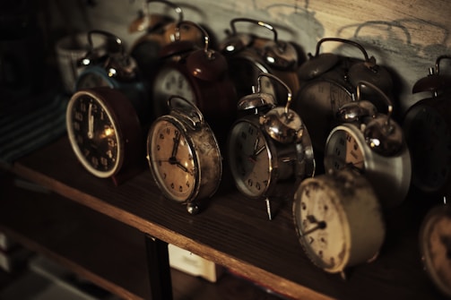 A collection of antique clocks arranged on a rustic wooden shelf.