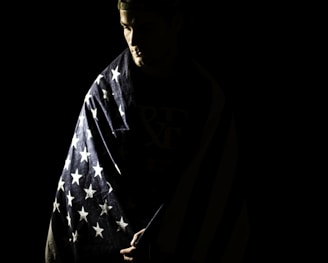 a man wrapped in an american flag in the dark