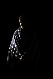 a man wrapped in an american flag in the dark