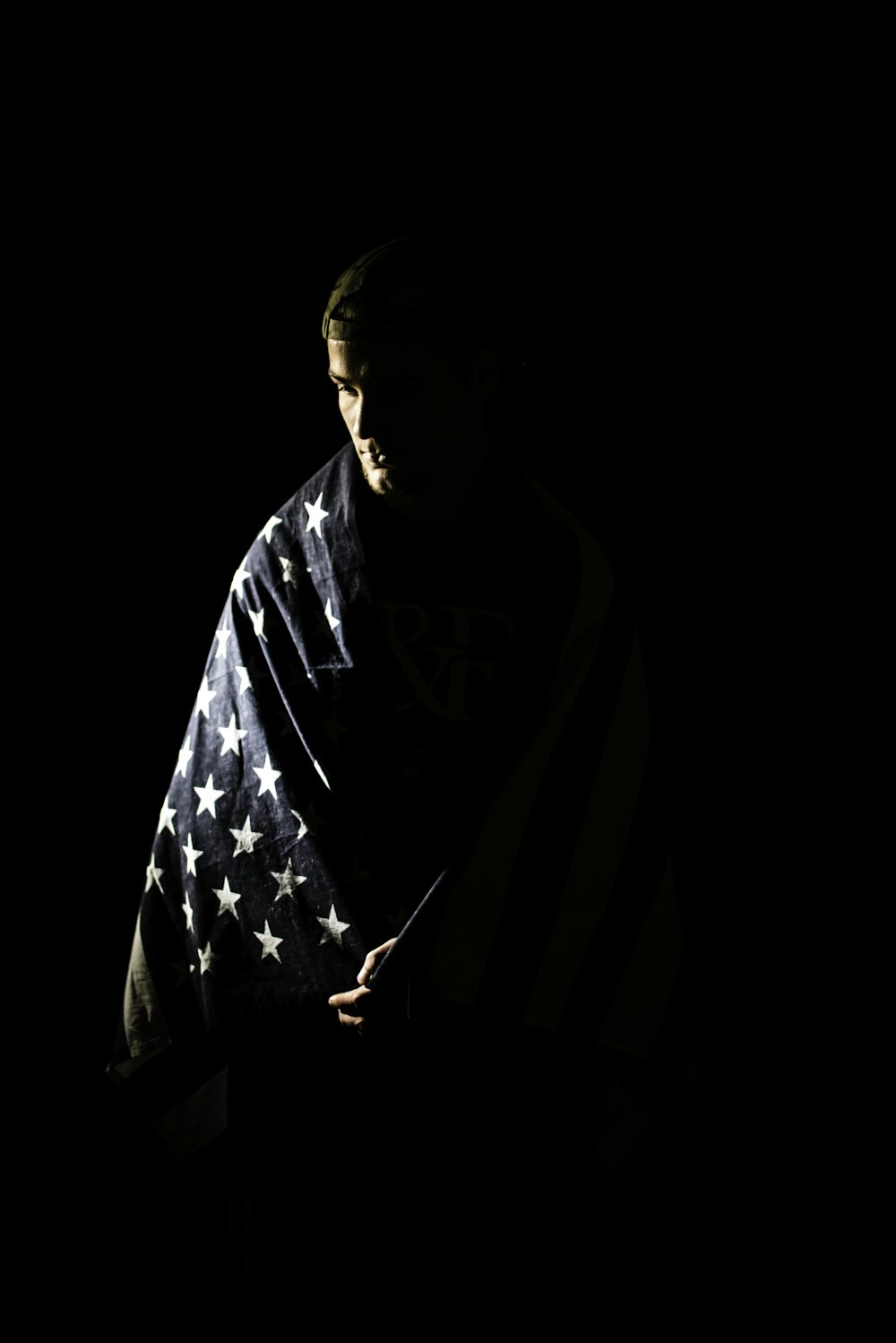 Um homem envolto em uma bandeira americana no escuro