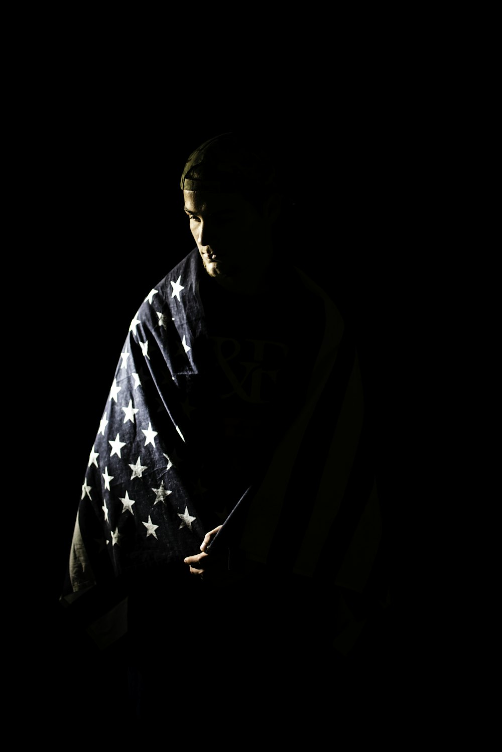 a man wrapped in an american flag in the dark