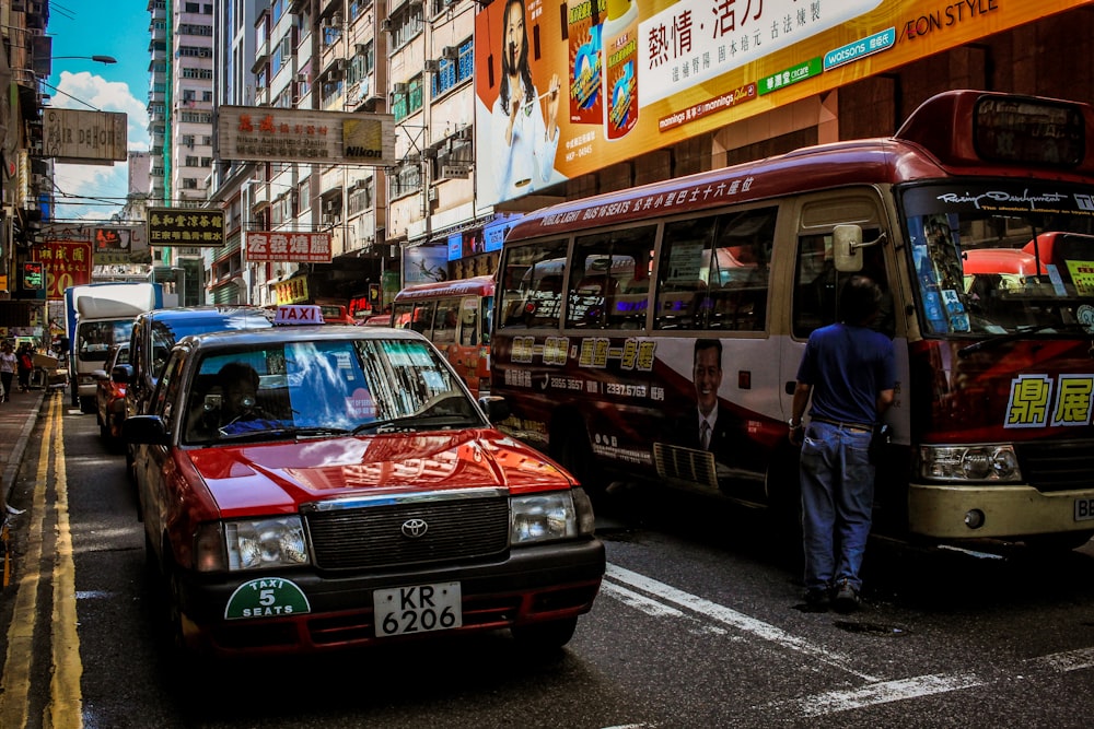 red Toyota car beside red bus