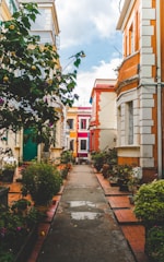 photo of narrow road beside concrete houses during daytime