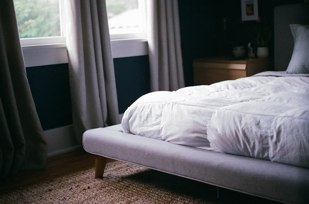 white bed by the window during daytime