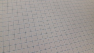 Close-up of a sheet of graph paper featuring a grid pattern of blue lines on a white background.