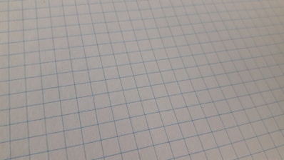 Close-up of a sheet of graph paper featuring a grid pattern of blue lines on a white background.