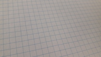 Close-up of a student sketching geometric shapes on graph paper.