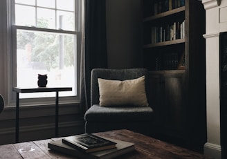 gray throw pillow on black chair by the window