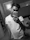 A young man trying on a sleek white shirt from km élégance in front of a mirror, with a bright room background.