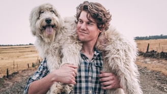 man carrying long-coated white dog