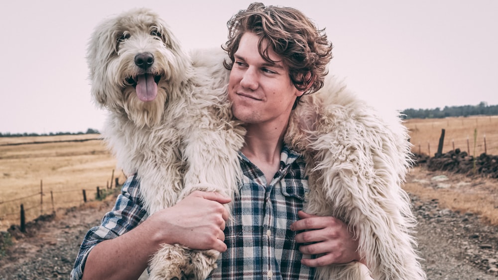 man carrying long-coated white dog