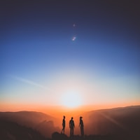 silhouette of three person standing on mountain