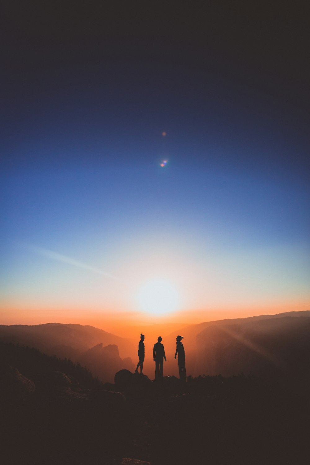 silueta de tres personas de pie en la montaña