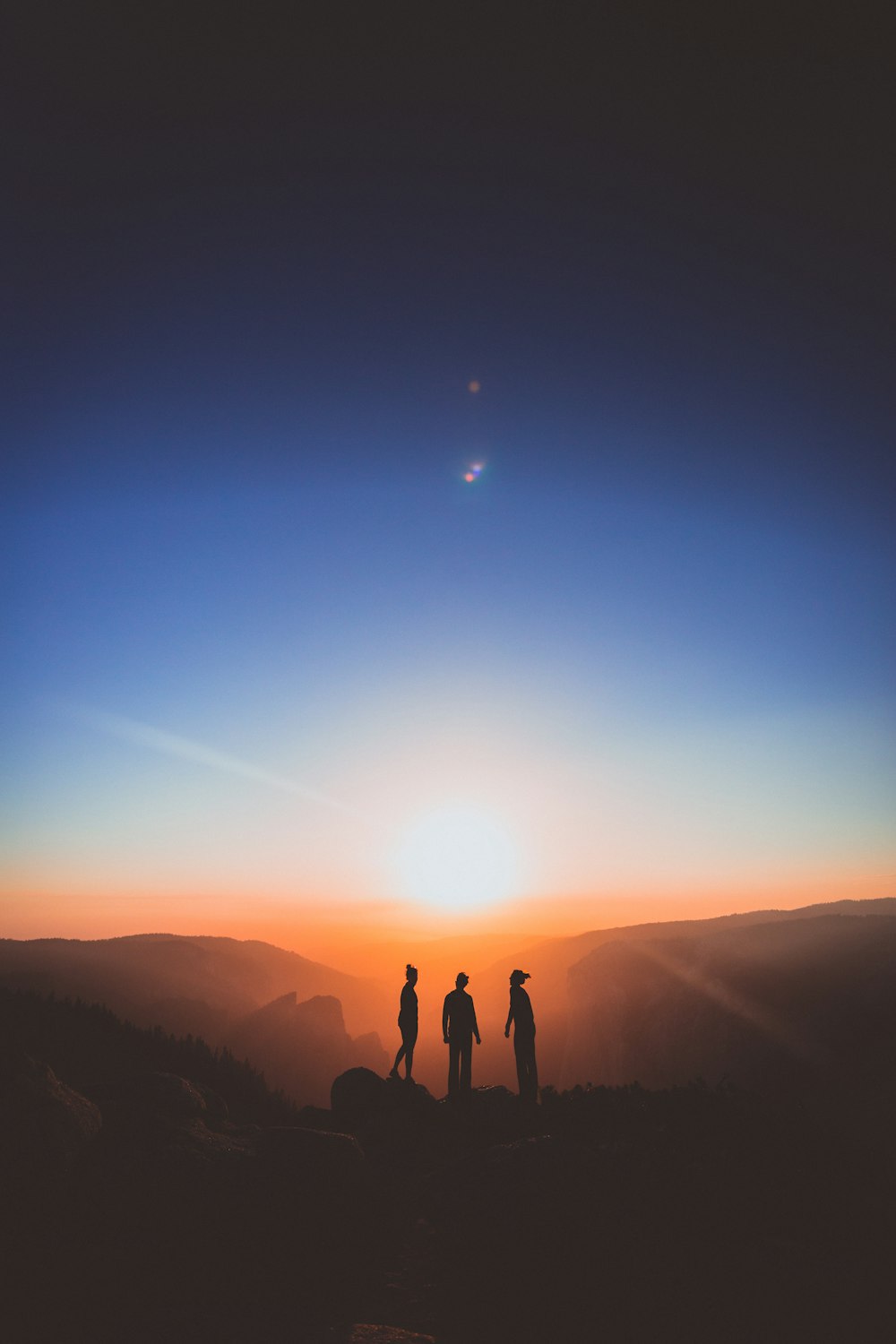 Silhouette einer dreiköpfigen Person, die auf dem Berg steht