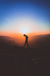 silhouette of man standing on mountain peak