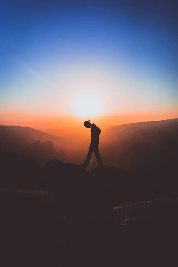 Silhouette of a lone figure standing on a mountain peak
