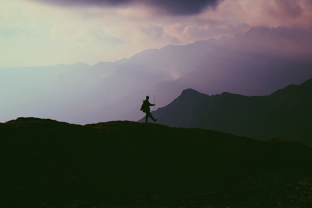 silhouette photo of person walking on mountain